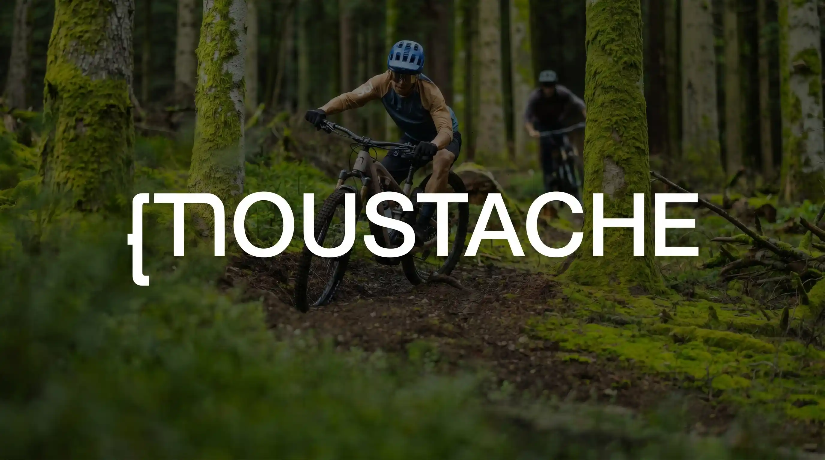 Ciclisti in mountain bike elettrica su un sentiero nel bosco con il logo Moustache.